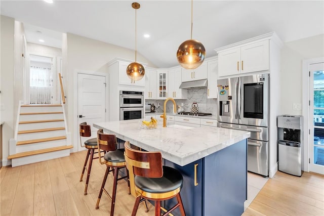 kitchen with appliances with stainless steel finishes, white cabinetry, under cabinet range hood, and tasteful backsplash