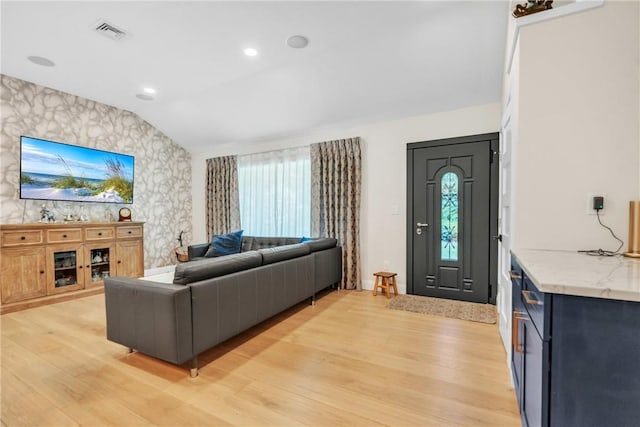 living room featuring lofted ceiling, visible vents, light wood-type flooring, plenty of natural light, and wallpapered walls