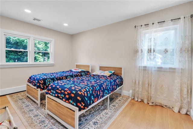 bedroom with baseboards, visible vents, wood finished floors, and recessed lighting