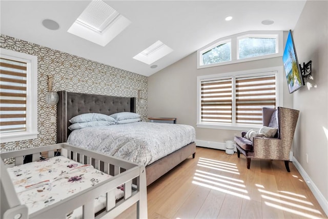 bedroom with lofted ceiling with skylight, an accent wall, baseboards, and wood finished floors