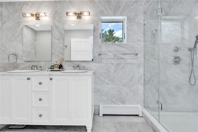 bathroom with tile walls, a sink, a shower stall, and baseboard heating