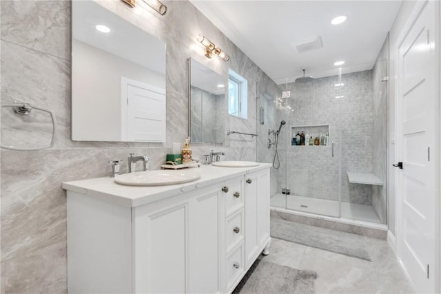 full bathroom featuring tiled shower, a sink, tile walls, and double vanity