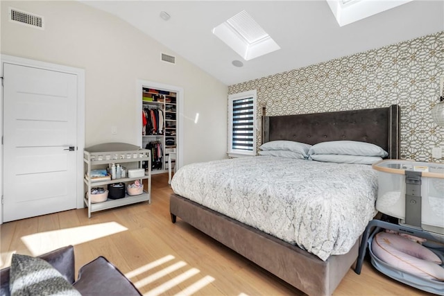 bedroom featuring an accent wall, visible vents, a spacious closet, and wallpapered walls