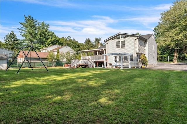 rear view of house with a yard, fence, and a wooden deck