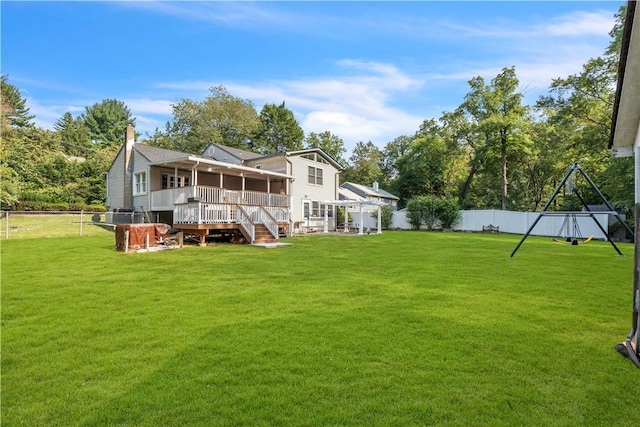 back of property with a sunroom, a fenced backyard, a lawn, and a wooden deck