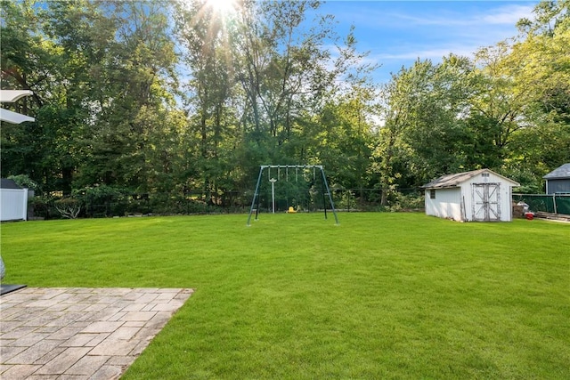 view of yard featuring a storage shed, an outbuilding, fence, and a playground