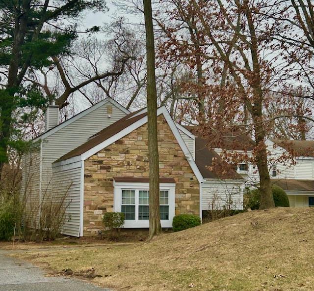 exterior space featuring a lawn, stone siding, and a chimney