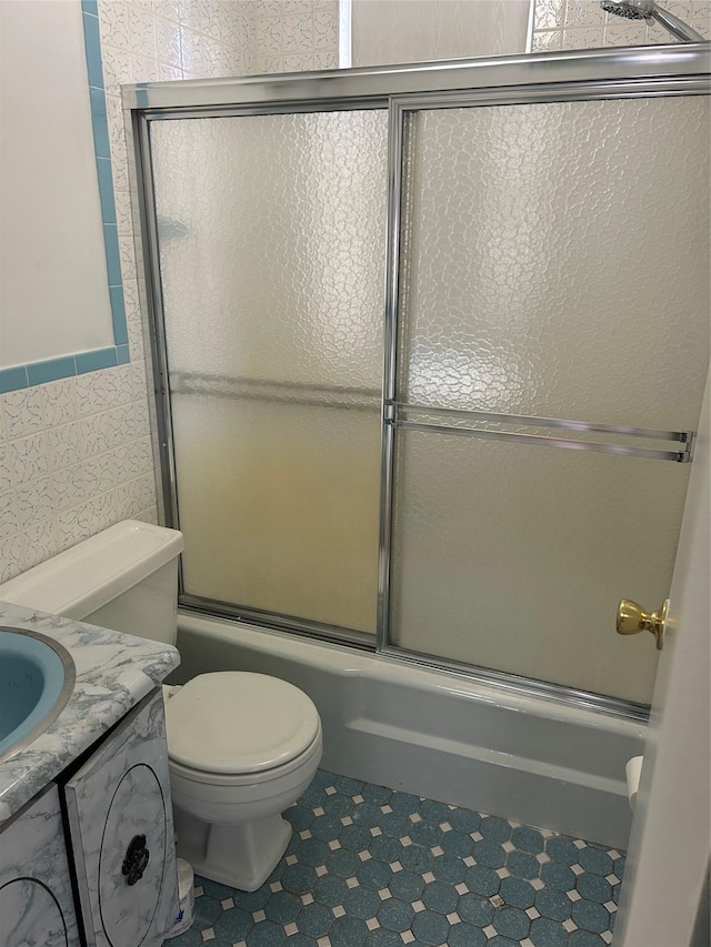 bathroom with combined bath / shower with glass door, vanity, and toilet