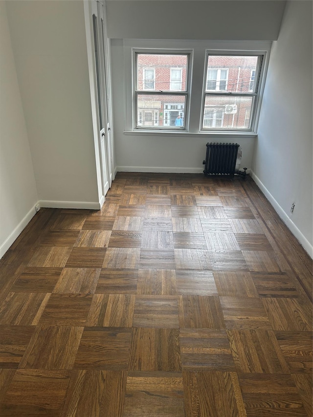 spare room with radiator heating unit and baseboards