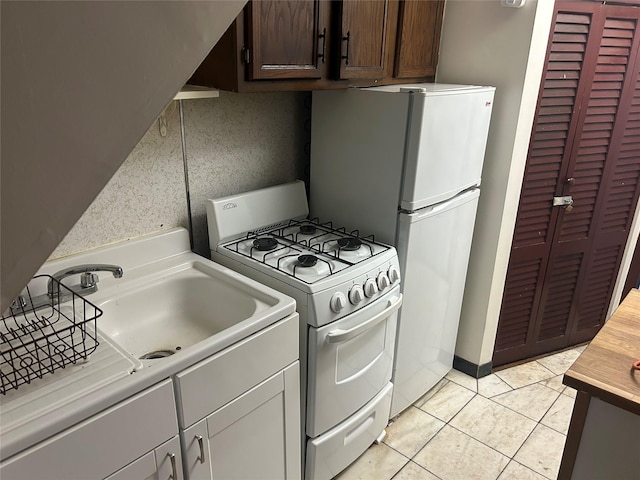 kitchen featuring light tile patterned floors, light countertops, a sink, dark brown cabinetry, and white appliances