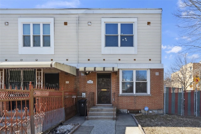 view of front of property featuring brick siding and fence