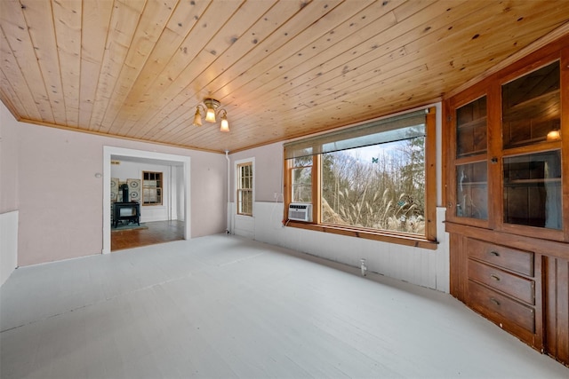 spare room with crown molding, wood ceiling, and a wood stove