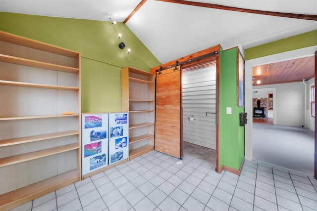 interior space with a barn door, lofted ceiling with beams, and light tile patterned floors