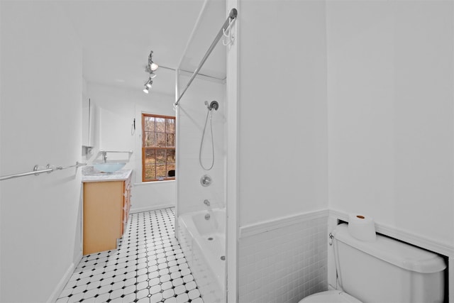 bathroom with toilet, wainscoting, rail lighting, bathtub / shower combination, and vanity