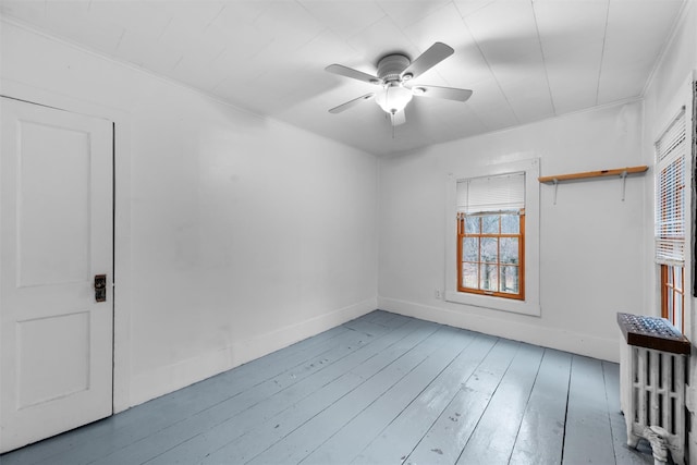 empty room featuring baseboards, ornamental molding, a ceiling fan, and hardwood / wood-style flooring