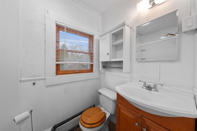 half bath featuring vanity, crown molding, toilet, and wainscoting