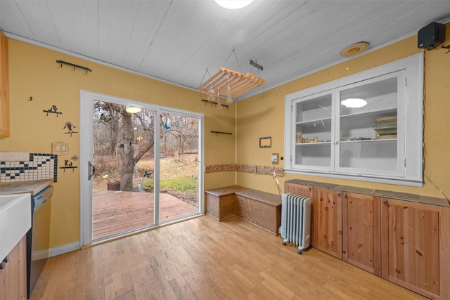 unfurnished dining area featuring radiator, wooden ceiling, and light wood finished floors