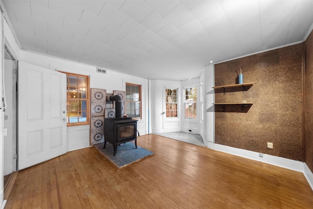 foyer with visible vents, wood finished floors, and a wood stove