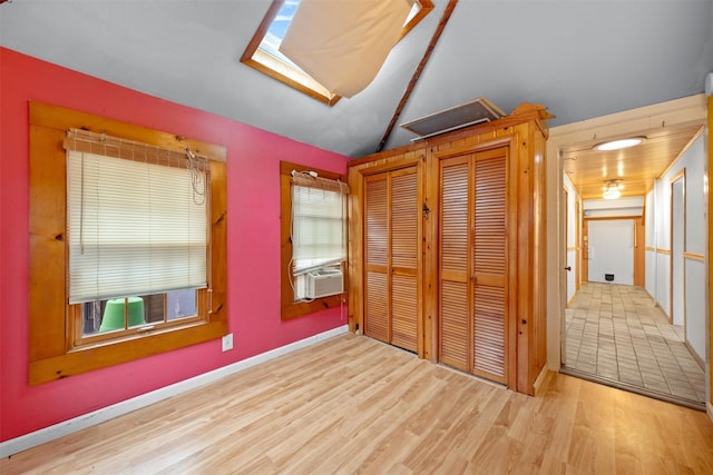 unfurnished bedroom featuring baseboards, wood finished floors, cooling unit, and lofted ceiling