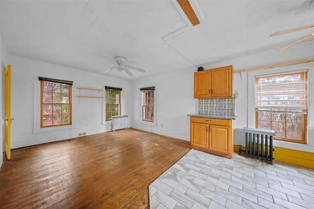 living room with light wood finished floors, a ceiling fan, visible vents, and radiator heating unit