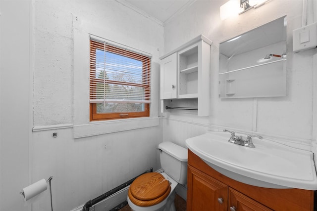 half bathroom featuring vanity, toilet, a wainscoted wall, a decorative wall, and ornamental molding