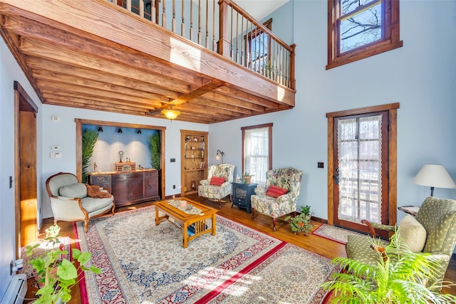 living room with a baseboard heating unit, wood finished floors, and baseboards