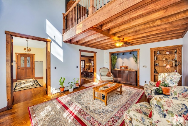 living room featuring a baseboard radiator, a towering ceiling, baseboards, and wood finished floors