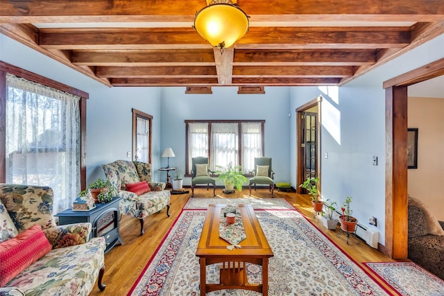 living area featuring a healthy amount of sunlight, beam ceiling, and wood finished floors