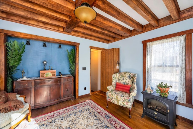 living area with beamed ceiling, wood finished floors, a wood stove, and baseboards