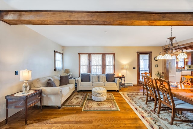 living area featuring a baseboard radiator, beam ceiling, and wood finished floors