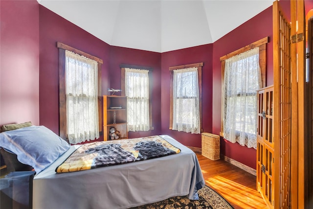 bedroom featuring baseboards, vaulted ceiling, and wood finished floors