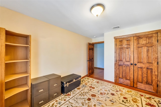 bedroom with visible vents, baseboards, and wood finished floors