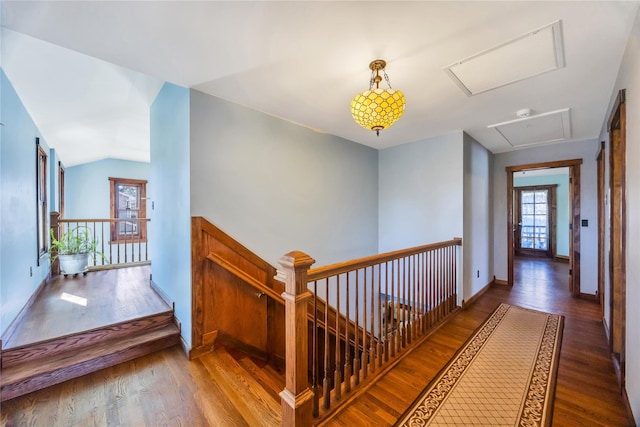 hallway with attic access, lofted ceiling, an upstairs landing, and wood finished floors