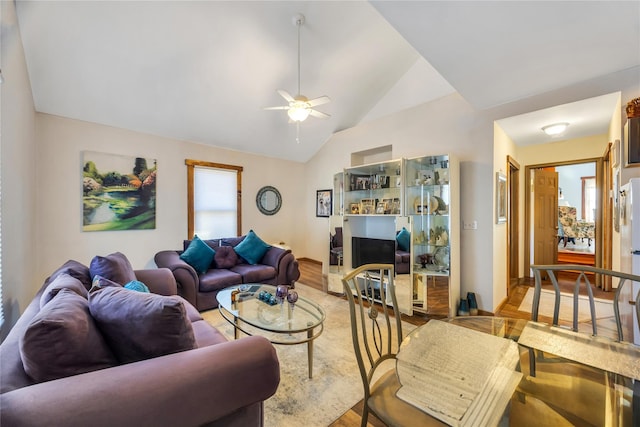 living area with lofted ceiling, ceiling fan, and light wood-style flooring