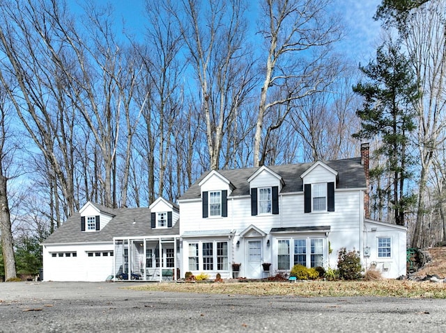 view of front of home featuring a garage, a chimney, and aphalt driveway