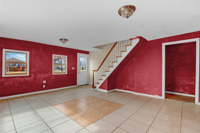 tiled foyer featuring stairway and baseboards