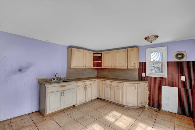 kitchen featuring open shelves, light tile patterned floors, cream cabinetry, and a sink