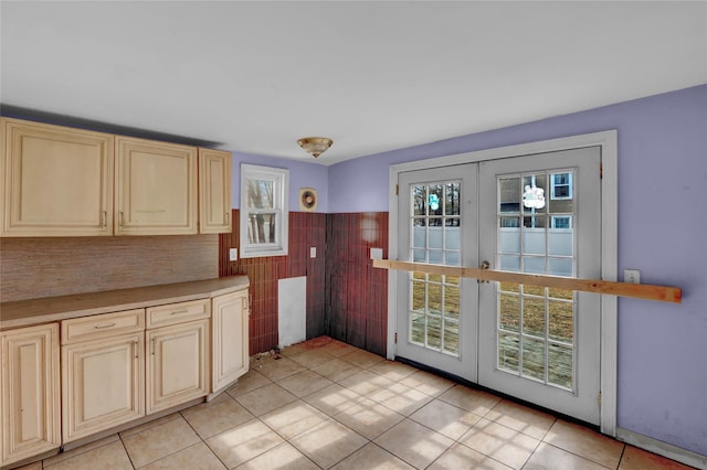 interior space featuring a healthy amount of sunlight, cream cabinets, tile walls, and french doors