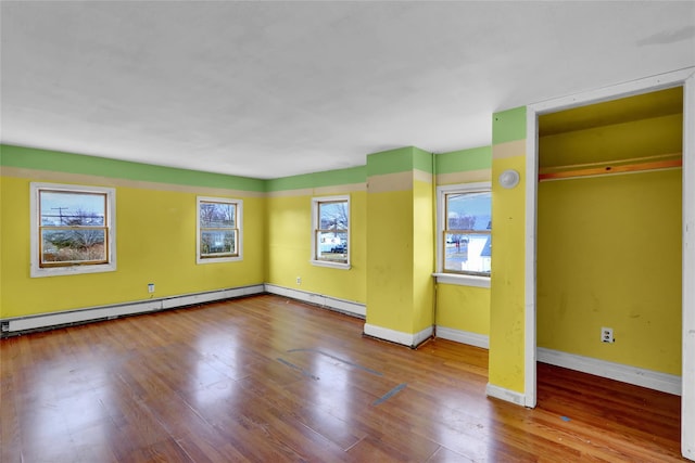 interior space featuring a baseboard heating unit, wood finished floors, and baseboards