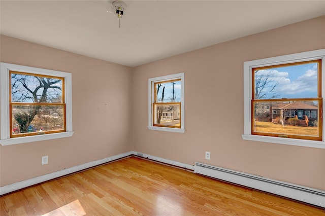 unfurnished room with light wood finished floors, a baseboard radiator, and baseboards