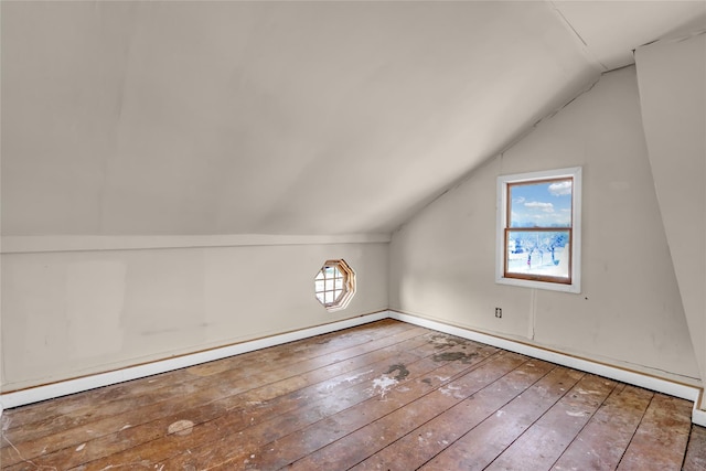 additional living space featuring a baseboard heating unit, wood-type flooring, lofted ceiling, and a wealth of natural light