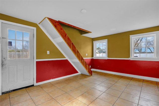 foyer entrance with stairs, light tile patterned flooring, and baseboards