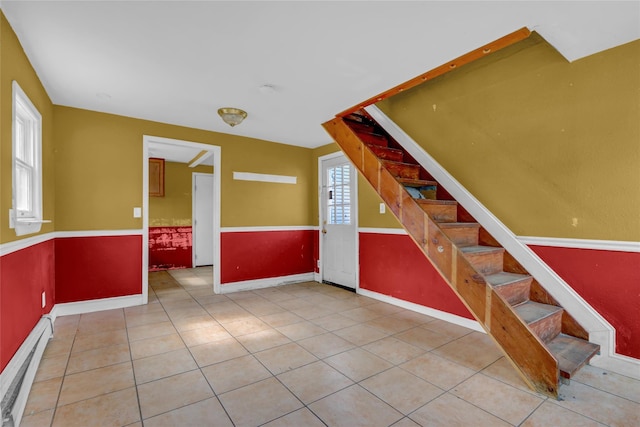 entryway featuring tile patterned flooring, stairs, a baseboard heating unit, and baseboards