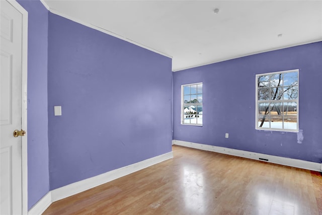 unfurnished room with plenty of natural light, wood finished floors, and baseboards