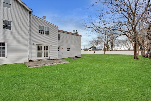 rear view of house featuring french doors, a lawn, and fence