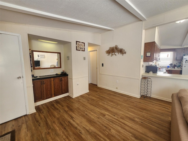 interior space with lofted ceiling with beams, a textured ceiling, and wood finished floors