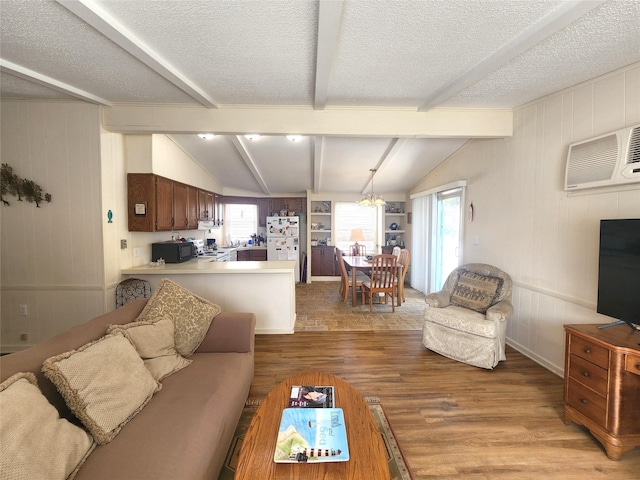 living room featuring light wood-style flooring, a wealth of natural light, vaulted ceiling with beams, and a textured ceiling