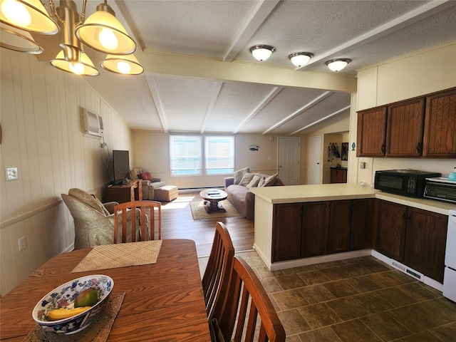 kitchen with light countertops, open floor plan, black microwave, beamed ceiling, and a peninsula