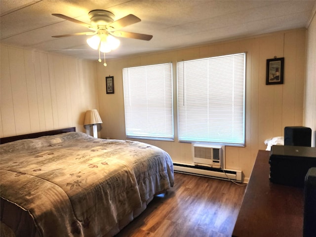 bedroom featuring dark wood-style floors, a baseboard radiator, a wall unit AC, and ceiling fan