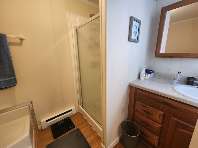 bathroom with a stall shower, baseboard heating, wood finished floors, and vanity